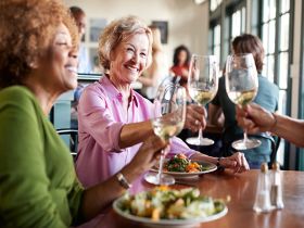 A group of senior women raising wine glasses in a toast